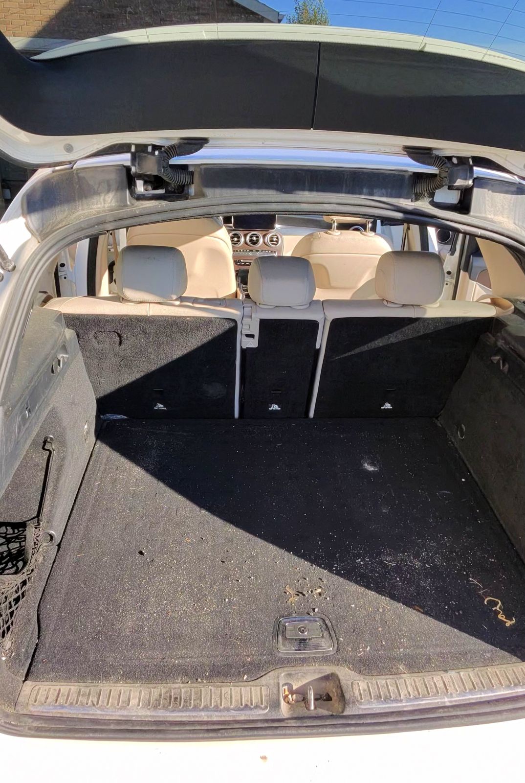 Mercedes cargo area before detailing, carpet covered in debris